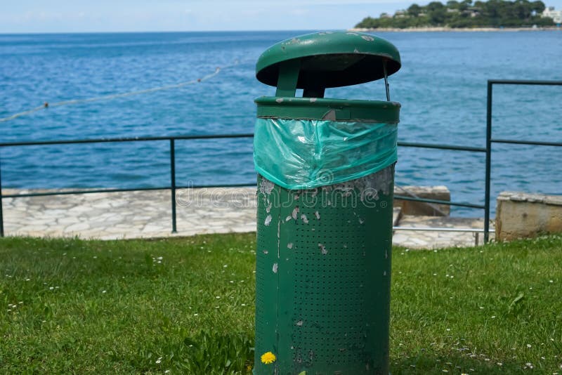 Green trash bin by the sea on a sunny day, concept of environmental protection, waste management, public cleanliness royalty free stock photos