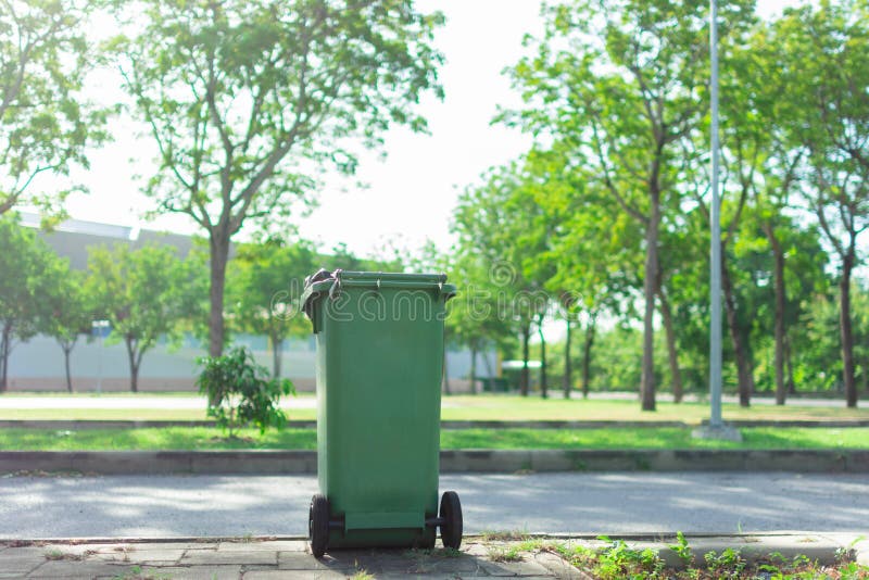 Green trash in the garden. Moulded plastic, wheeled waste bin in The park. Trash or bin is tools of Waste management. royalty free stock photography