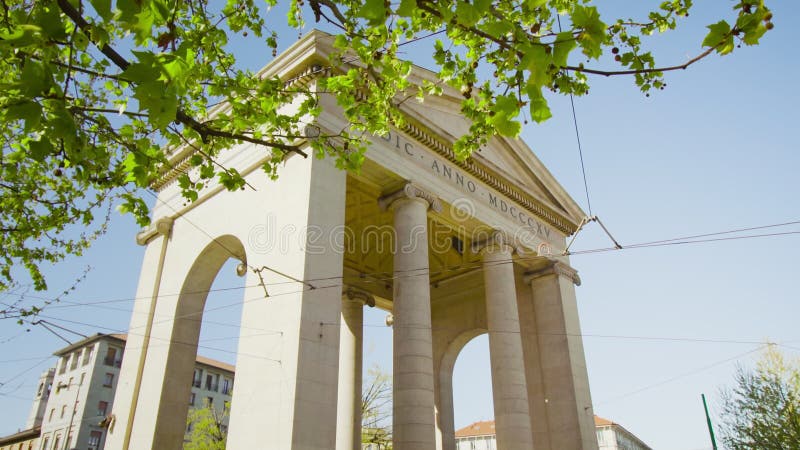 Green tree grows against white arch in Ticinese on sunny day