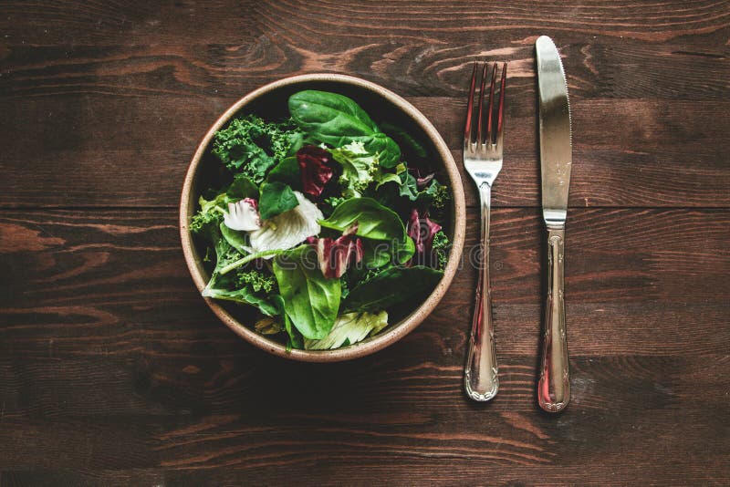 Green vegan Breakfast in a bowl with various leaves and cutlery, on wooden background, top view. Clean eating, dieting, vegan royalty free stock photo Green vegan Breakfast in a bowl with various leaves and cutlery, on wooden background, top view. Clean eating, dieting, vegan royalty free stock photo