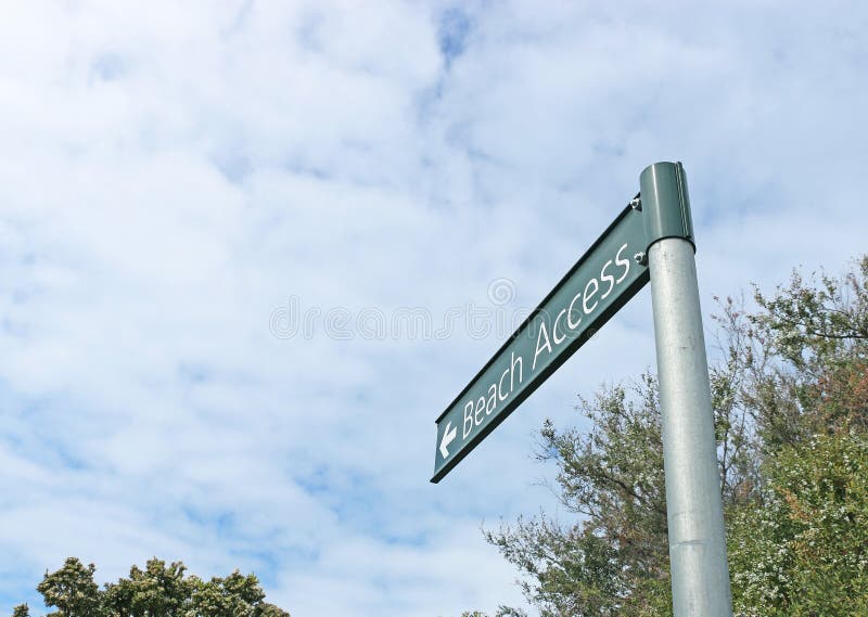 Green and white beach access sign on beach foreshore stock photography