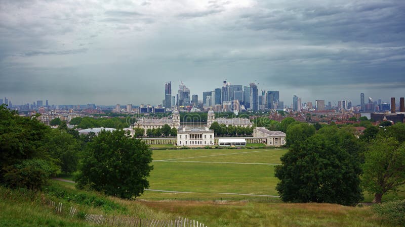 GREENWICH, LONDON, UNITED KINGDOM - JUNE 24, 2019: Panoramic view from Greenwich Park towards Canary Wharf business district 免版税库存照片 GREENWICH, LONDON, UNITED KINGDOM - JUNE 24, 2019: Panoramic view from Greenwich Park towards Canary Wharf business district 免版税库存照片