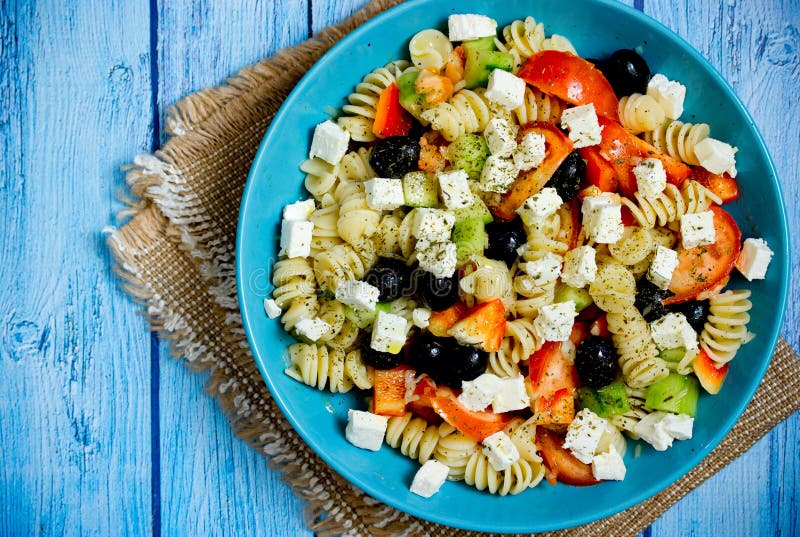 Grekisk sallad med nya grönsaker, fetaost, pasta och svarta oliv royaltyfri bild Grekisk sallad med nya grönsaker, fetaost, pasta och svarta oliv royaltyfri bild