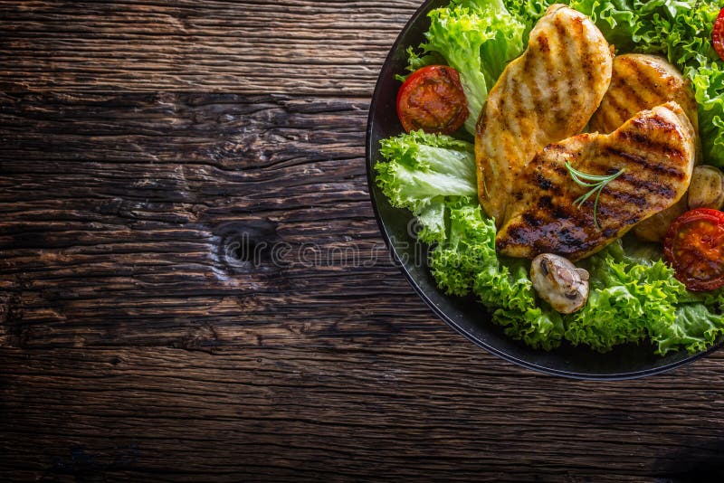 Grelhe o peito de frango Roasted e grelhe o peito de frango com os tomates e os cogumelos da salada da alface fotografia de stock Grelhe o peito de frango Roasted e grelhe o peito de frango com os tomates e os cogumelos da salada da alface fotografia de stock