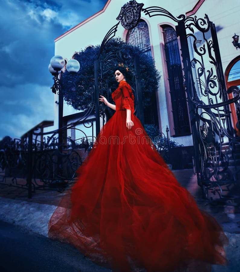 Beautiful brunette girl with long hair. She's in a vintage red dress with bare shoulders. The Queen walks near her castle. Background extraordinary castle. Gothic history. Fashionable toning. Creative computer colors. Beautiful brunette girl with long hair. She's in a vintage red dress with bare shoulders. The Queen walks near her castle. Background extraordinary castle. Gothic history. Fashionable toning. Creative computer colors.