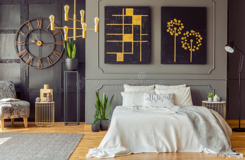 Grey blanket on bed against the wall with black posters in bedroom interior with clock. Real photo