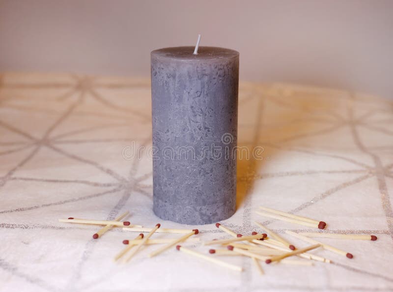 Grey Candle and Matchsticks on a White and Silver Blanket Surface