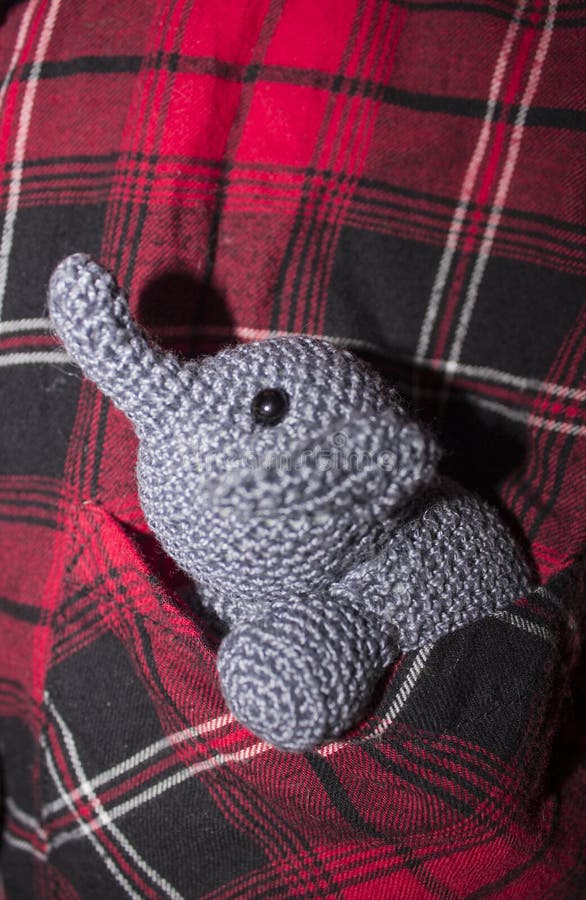 Grey elephant crocheted sitting in plaid shirt pocket. Little grey elephant crocheted sitting in a pocket shirt with red, black and white cage stock image Grey elephant crocheted sitting in plaid shirt pocket. Little grey elephant crocheted sitting in a pocket shirt with red, black and white cage stock image