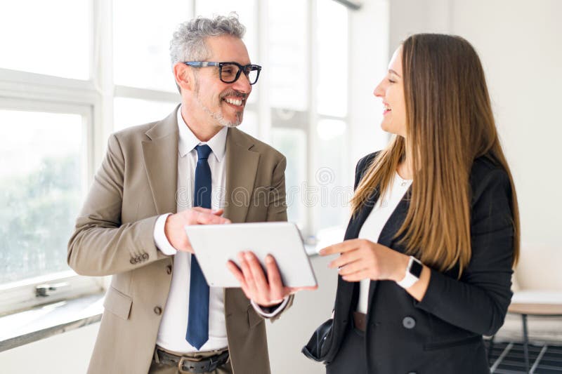 Grey-haired businessman engages with younger colleague, sharing a tablet royalty free stock images