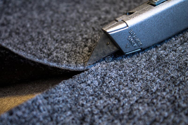 Grey roll of carpet and a knife for slicing royalty free stock image