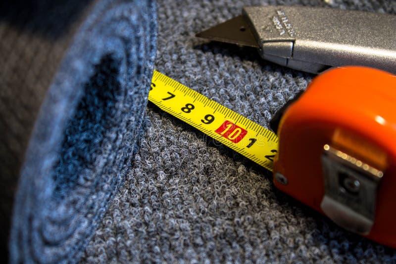 Grey roll of carpet and a knife for slicing royalty free stock photos