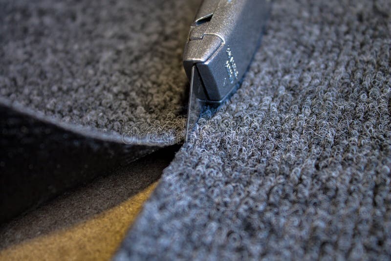 Grey roll of carpet and a knife for slicing stock images