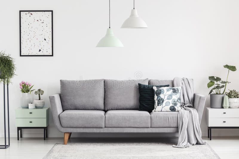Grau sofa zwischen den Schränken mit Pflanzen in weiß-Wohnzimmer-Interieur-mit-Lampen-und-poster.
