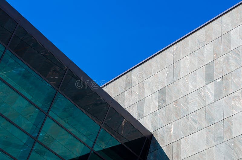 Grey stone facade of a modern building with glass windows