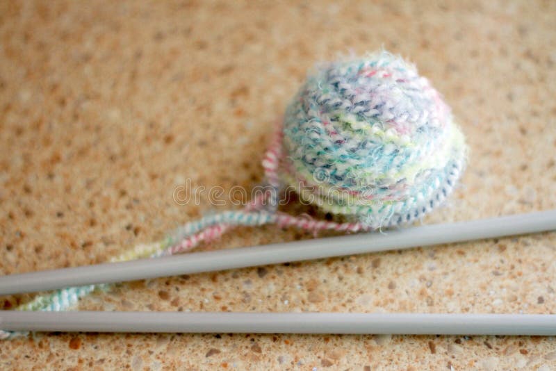 Grey wires for knitting together with a tug of threads of different color lie on a surface of gentle color royalty free stock photos Grey wires for knitting together with a tug of threads of different color lie on a surface of gentle color royalty free stock photos