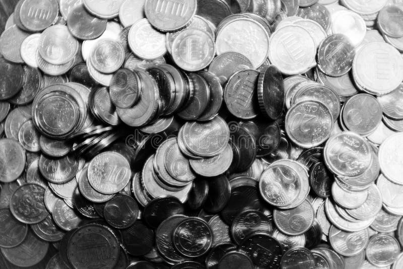 Greyscale closeup of old coins under the light with a blurry background.