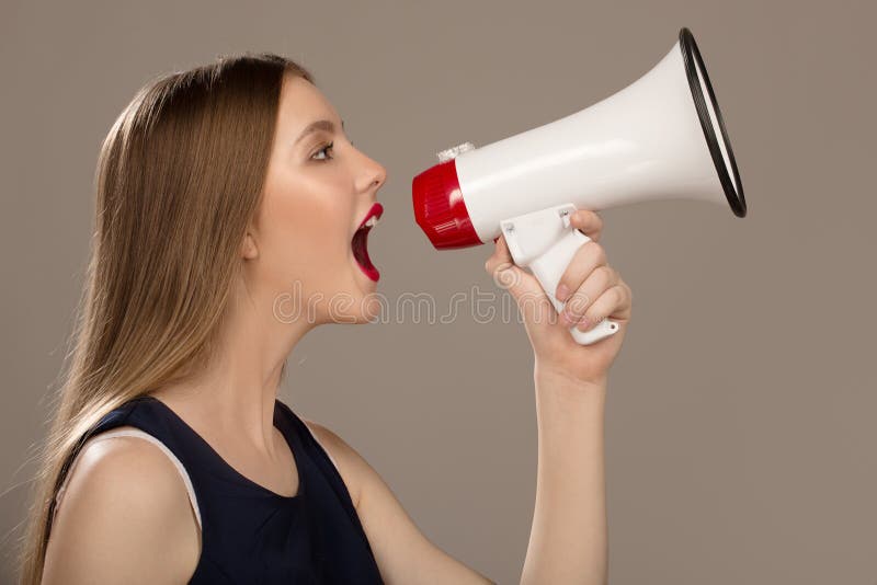 Grido della donna in un megafono Fondo grigio immagini stock Grido della donna in un megafono Fondo grigio immagini stock