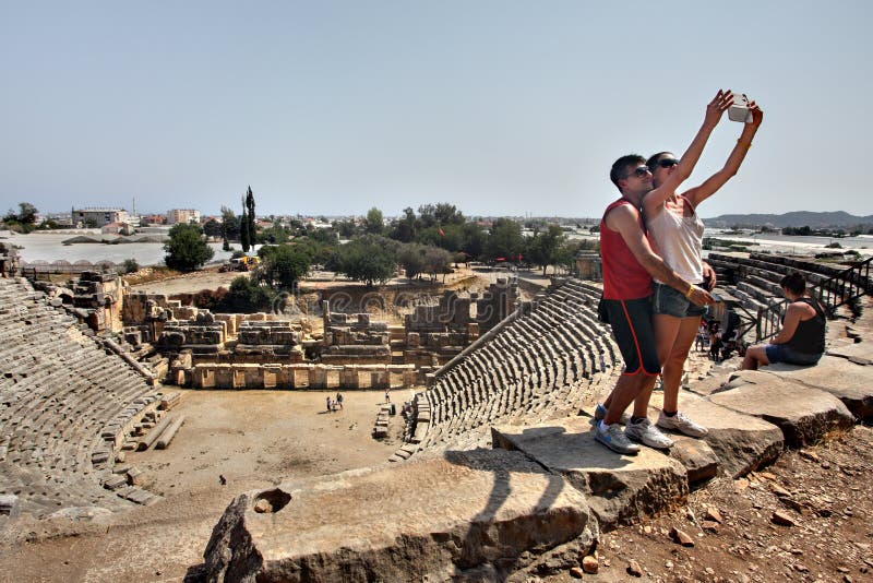 Myra, Antalya, Turkey - August 28, 2014: Myra, Antalya, Turkey - August 28, 2014: Ancient amphitheater, couple take a picture together while visiting a tourist attraction, smiling and having fun. Myra, Antalya, Turkey - August 28, 2014: Myra, Antalya, Turkey - August 28, 2014: Ancient amphitheater, couple take a picture together while visiting a tourist attraction, smiling and having fun.