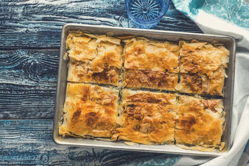 Griechisches Torte spanakopita in der Metallwanne auf der blauen Draufsicht des Holztischs stockfotos Griechisches Torte spanakopita in der Metallwanne auf der blauen Draufsicht des Holztischs stockfotos