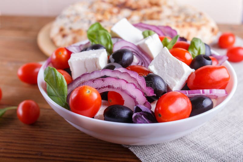 Griekse salade met verse kersentomaten, feta-kaas, zwarte olijven, basilicum en ui op houten achtergrond stock foto's Griekse salade met verse kersentomaten, feta-kaas, zwarte olijven, basilicum en ui op houten achtergrond stock foto's