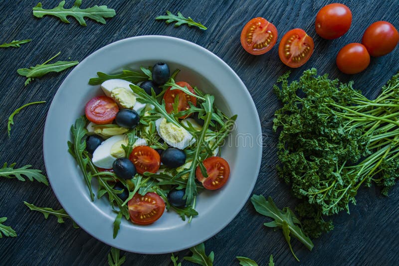 Griekse salade met verse tomaten, arugula, eieren, olijven met olijfolie op een donkere houten achtergrond Gezond voedsel Veggie royalty-vrije stock fotografie Griekse salade met verse tomaten, arugula, eieren, olijven met olijfolie op een donkere houten achtergrond Gezond voedsel Veggie royalty-vrije stock fotografie
