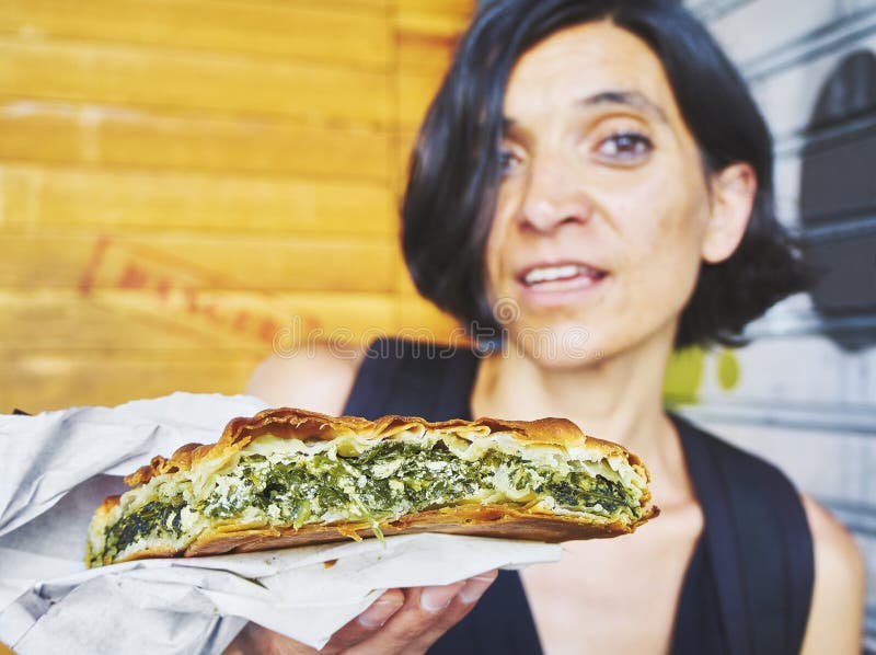 Griekse vrouw die een een traditionele Spanakotiropita, een Spinazie en Feta-pastei eten stock foto Griekse vrouw die een een traditionele Spanakotiropita, een Spinazie en Feta-pastei eten stock foto