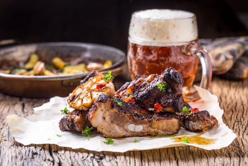 Grigli le costole arrostite succose della carne di maiale delle costole di carne di maiale con la birra alla spina sulla tavola d fotografia stock libera da diritti Grigli le costole arrostite succose della carne di maiale delle costole di carne di maiale con la birra alla spina sulla tavola d fotografia stock libera da diritti