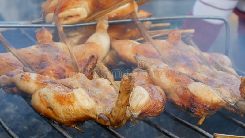 Griglia della carcassa dell'intero pollo messa insieme sul bastone di legno che griglia sulla griglia Alimento Tailandia della vi