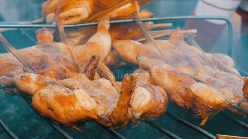 Griglia della carcassa dell'intero pollo messa insieme sul bastone di legno che griglia sulla griglia Alimento Tailandia della vi