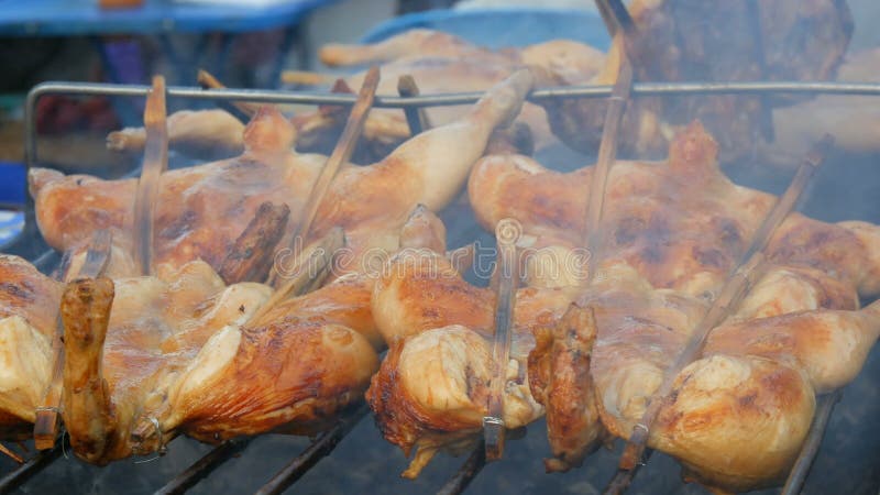 Griglia della carcassa dell'intero pollo messa insieme sul bastone di legno che griglia sulla griglia Alimento Tailandia della vi