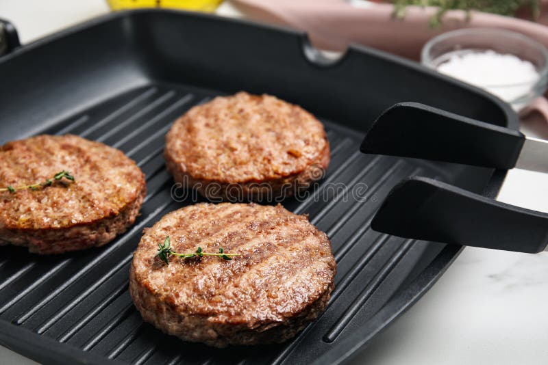 Grill Pan with Tasty Fried Hamburger Patties on White Table Stock Photo