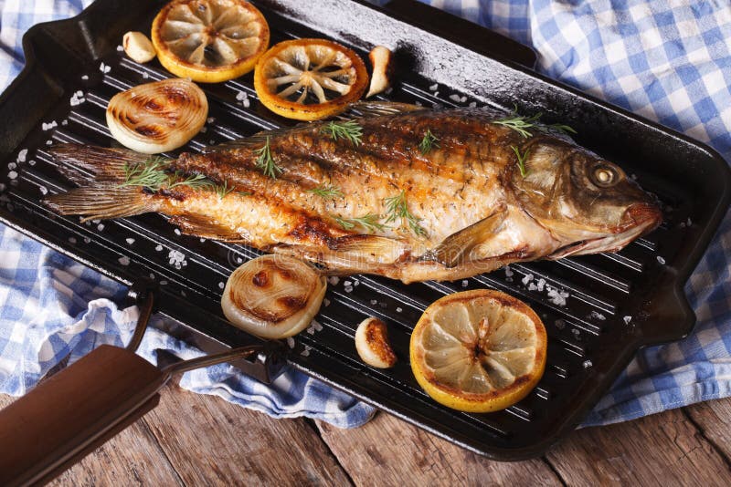 Grillad fiskkarp med citronen på ett stekpannagaller som är horisontal arkivbild Grillad fiskkarp med citronen på ett stekpannagaller som är horisontal arkivbild