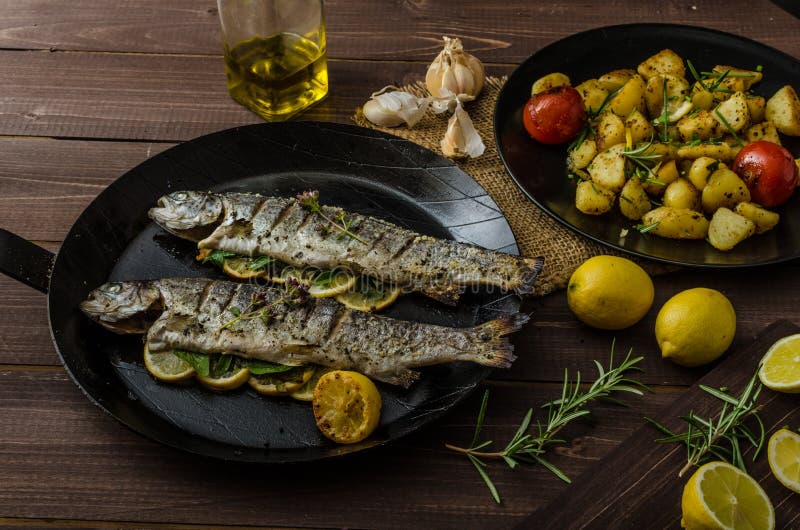 Grillad forell med grillade potatisar royaltyfri bild Grillad forell med grillade potatisar royaltyfri bild