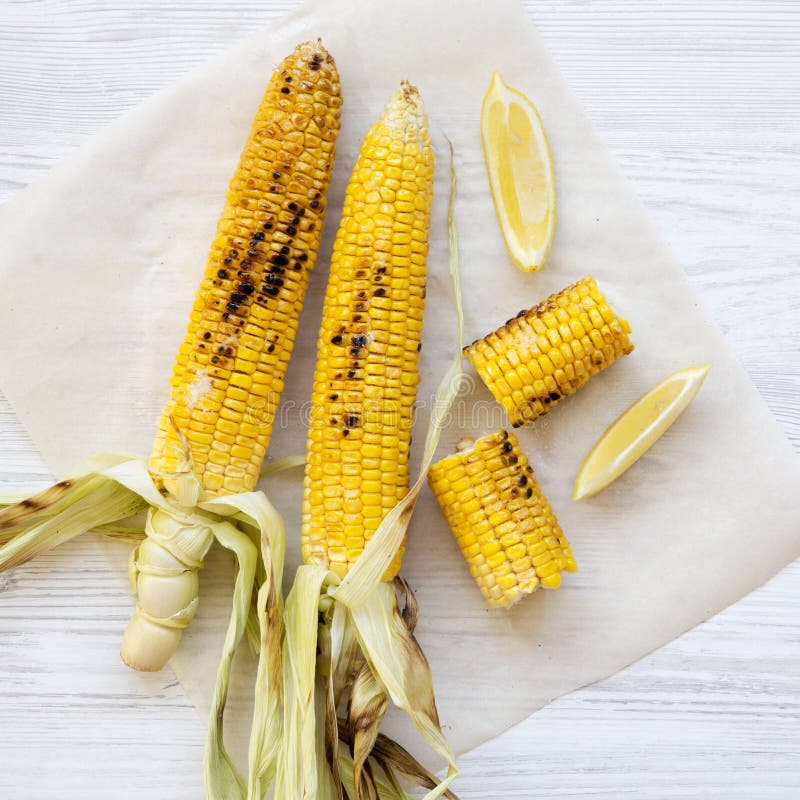 Grillad havre p? majskolven med skivor av citronen ?ver vit tr?bakgrund, n?rbild Sommarmat B?sta sikt, fr?n ?ver som ?r ?ver huvu royaltyfria foton Grillad havre p? majskolven med skivor av citronen ?ver vit tr?bakgrund, n?rbild Sommarmat B?sta sikt, fr?n ?ver som ?r ?ver huvu royaltyfria foton