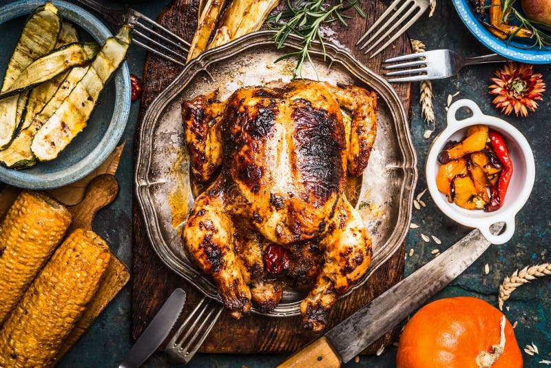 Grillad hel kalkon eller höna med organisk skördgrönsaker och pumpa för tacksägelsematställe på lantlig tabellbakgrund royaltyfri foto Grillad hel kalkon eller höna med organisk skördgrönsaker och pumpa för tacksägelsematställe på lantlig tabellbakgrund royaltyfri foto