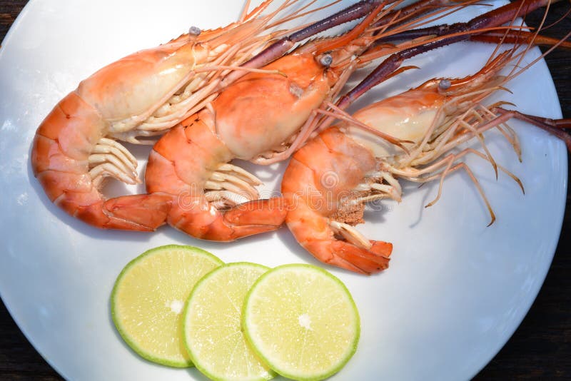 Grillad räka med citronen på den vita plattan på den wood tabellen, havsmat royaltyfri bild Grillad räka med citronen på den vita plattan på den wood tabellen, havsmat royaltyfri bild