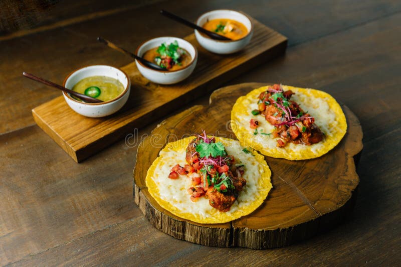 Grillade fega taco med tomatsallad tjänade som på träskärbräda med olika såser, och mexikanen torkade chili arkivfoton Grillade fega taco med tomatsallad tjänade som på träskärbräda med olika såser, och mexikanen torkade chili arkivfoton