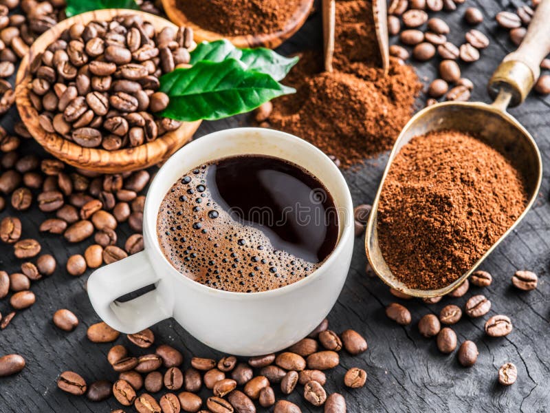 Grillade kaffebönor, jordkaffe och kopp kaffe på trä arkivbilder