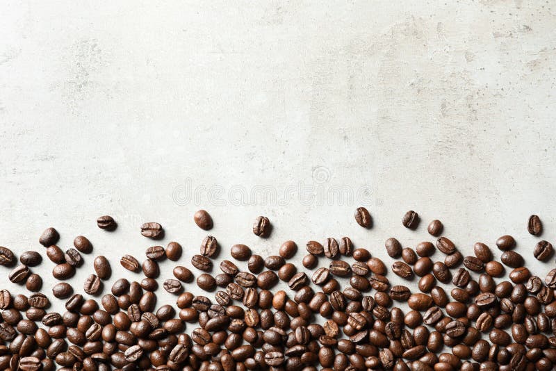 Grillade kaffebönor på grå bakgrund med utrymme royaltyfri foto