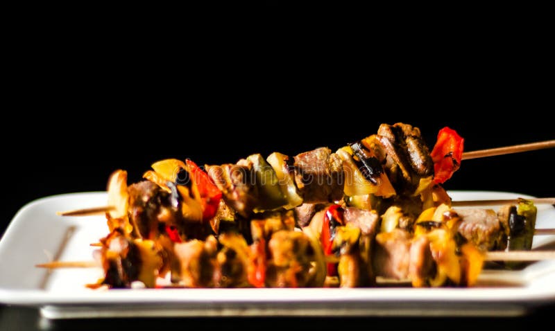 Grillade steknålar av kött och grönsaker på en träfärgrik och smaklig maträtt för bräde, royaltyfri bild Grillade steknålar av kött och grönsaker på en träfärgrik och smaklig maträtt för bräde, royaltyfri bild