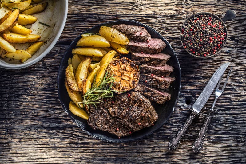 Grilled beef Rib Eye steak with garlic american potatoes rosemary salt and spices