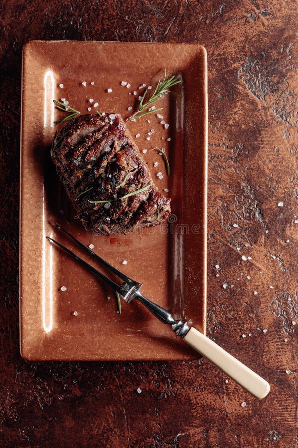 Grilled Beef Steak with Rosemary and Salt on a Brown Background Stock