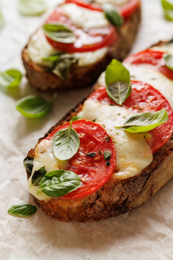 Grilled caprese sandwich based on sourdough bread with the addition of tomatoes, mozzarella cheese, fresh basil and olive oil on a light background close up view. Addition salad stock images, royalty-free photos and pictures