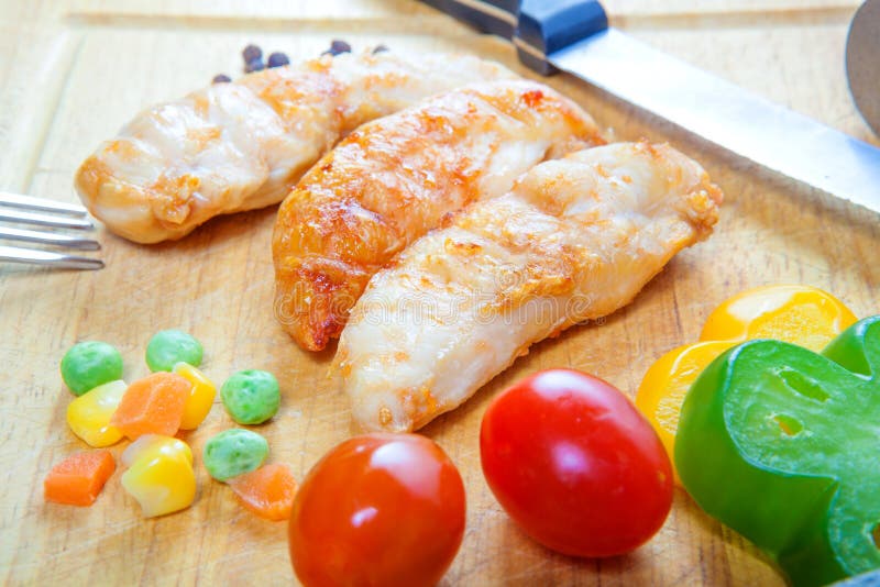 Grilled Chicken Breast with Fresh Vegetables on Cutting Board Stock