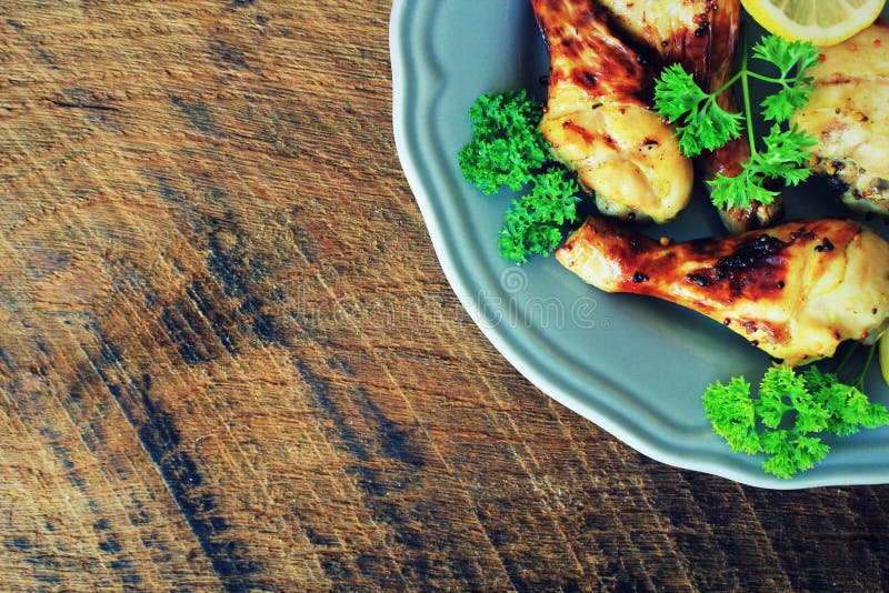 Grilled chicken legs with mustard on plate. Rustic dinner background . Top view