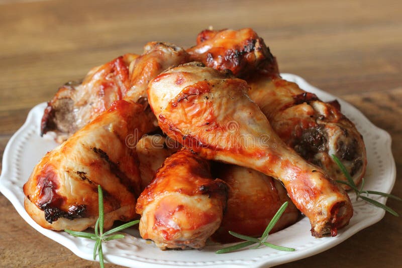 Grilled chicken legs on white plate .Rustic dinner background
