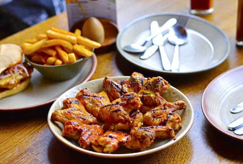 Grilled Chicken Wings & Chips on Restaurant`s Dining Table Stock Image