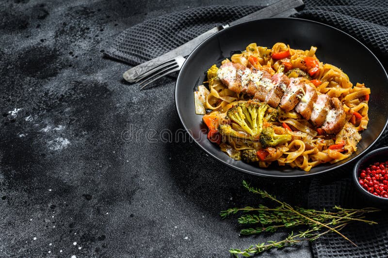 Grilled duck breast with Udon noodles and vegetables. Black background. Top view. Copy space