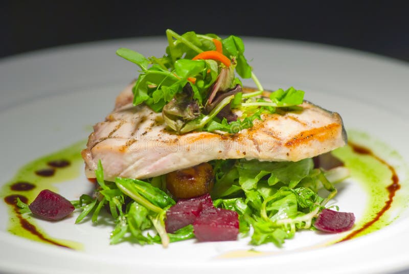 Piastra con filetto di pesce alla griglia, baby crescione, baby rucola, arrosto di radice di barbabietola, barbabietola, salsa di erbe e olio.