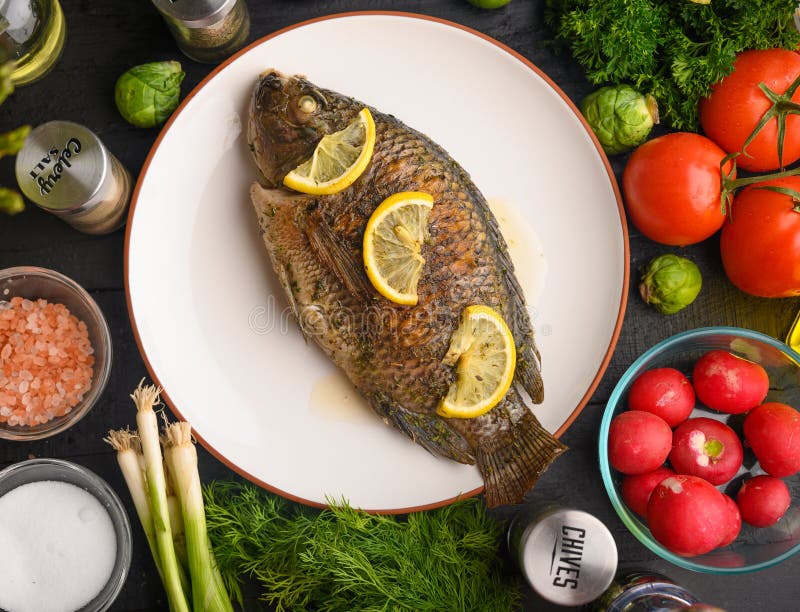 Grilled fish with fresh vegetables, on a wooden black background. I also eat healthy food. Seafood